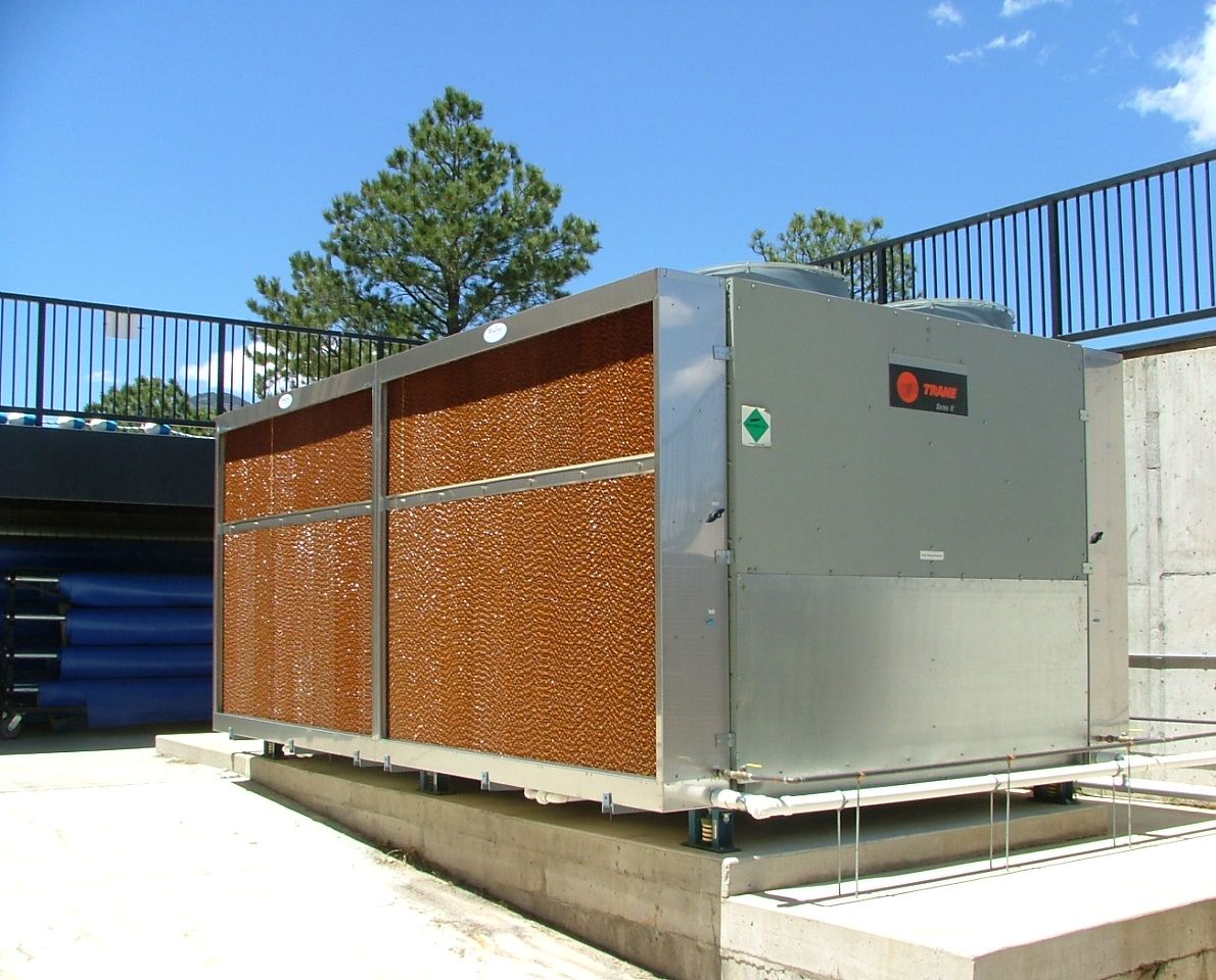 Evaporative pre-cooler media panels mounted along the side of an outdoor air-cooled chiller