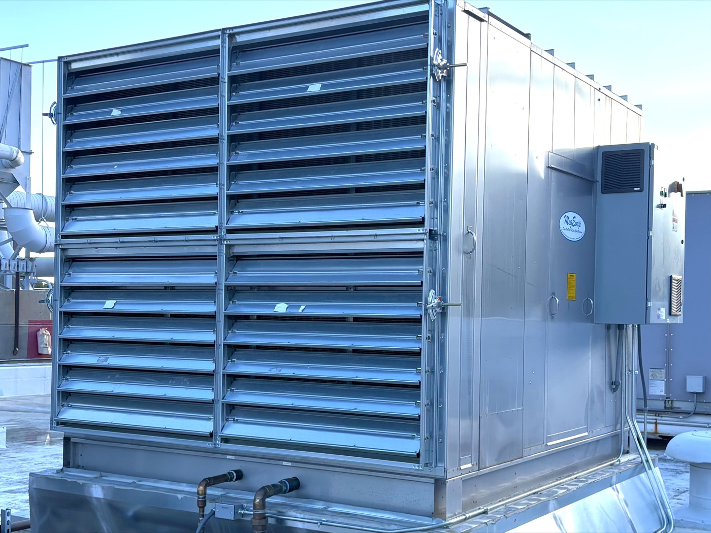 A large stainless steel MegEvap packaged evaporative cooler with louvered intakes, installed on a rooftop