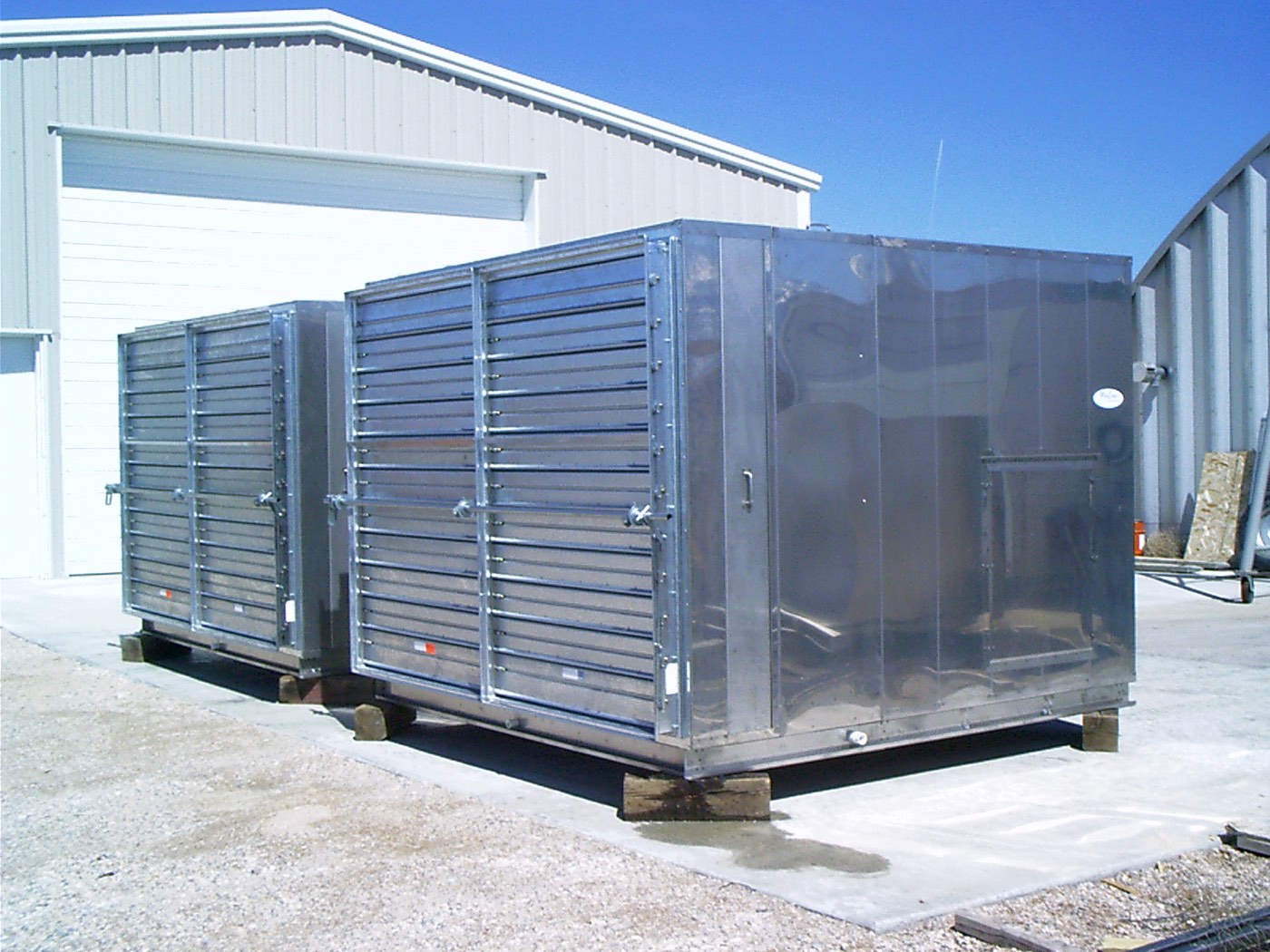 Two stainless steel MegEvap packaged evaporative coolers with louvered intakes, set on a concrete pad