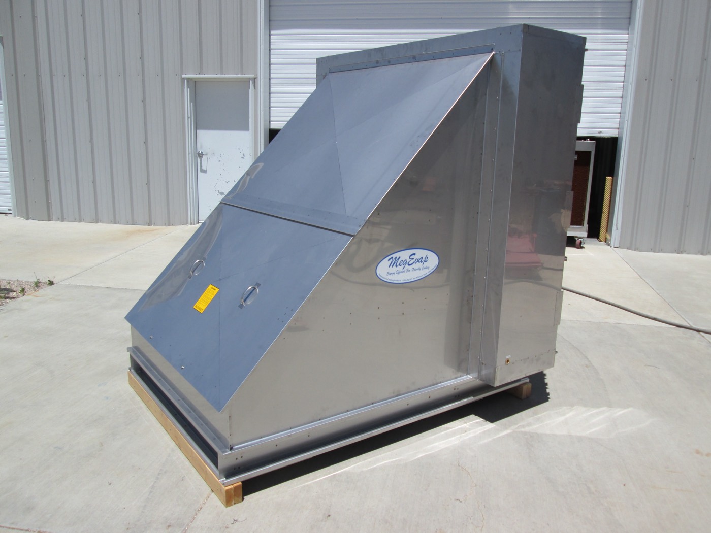 A stainless steel MegEvap RTA-18 cooler on a pallet, showing the angled fan housing